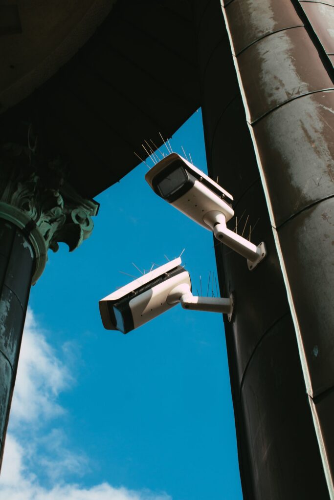 Two security cameras mounted on a building against a blue sky