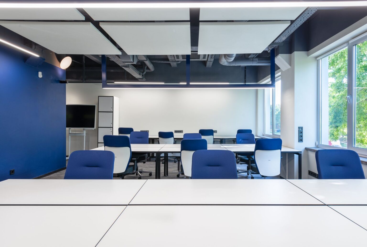 Modern open-plan office with desks, blue chairs and large windows